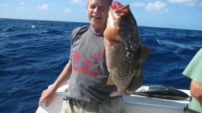 A man on a boat holding a large fish