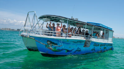 A large group on the Crab Island Runner boat. The boat has an under water image on the side with the text "Crab Island Runner"