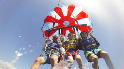 Three males parasailing in Destin, Florida in a red and white parascender