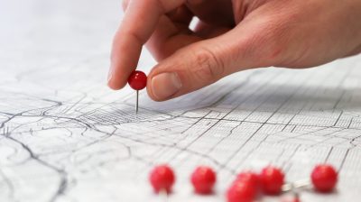 A map with push pins on top, with one pushpin marking a location