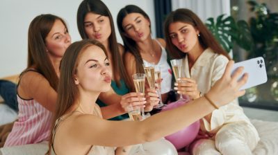 Women posing for a selfie while holding drinks during a Destin bachelorette party