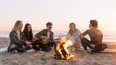 a group of friends having a bonfire at the beach