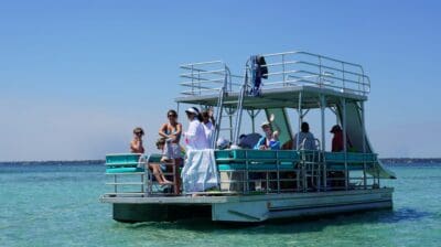 Double decker pontoon boat with an upper deck and water slide anchored at Crab Island in Destin, FL